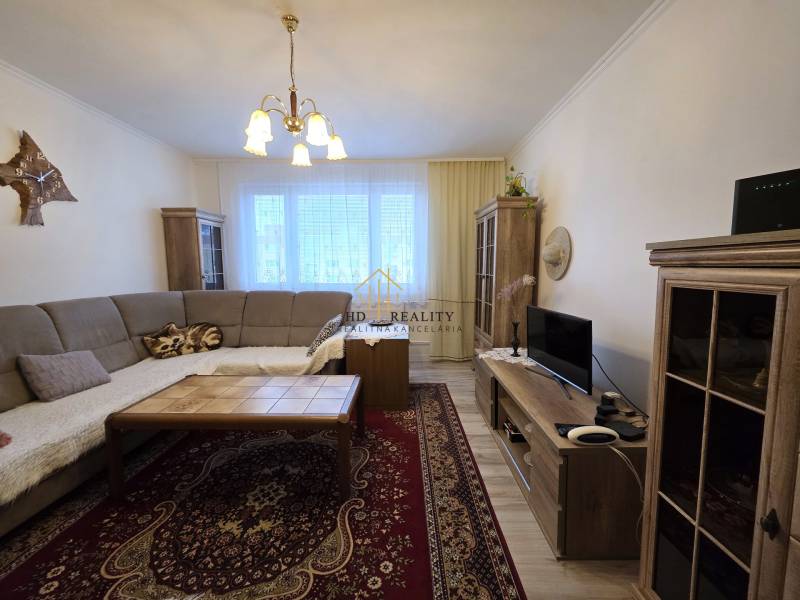 Living room in a 3-room apartment with a corner sofa and a floor with a wooden decor.
