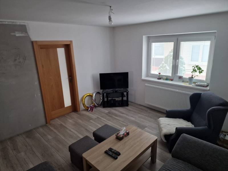 Living room in a family house with wood-patterned flooring, a television, and seating.