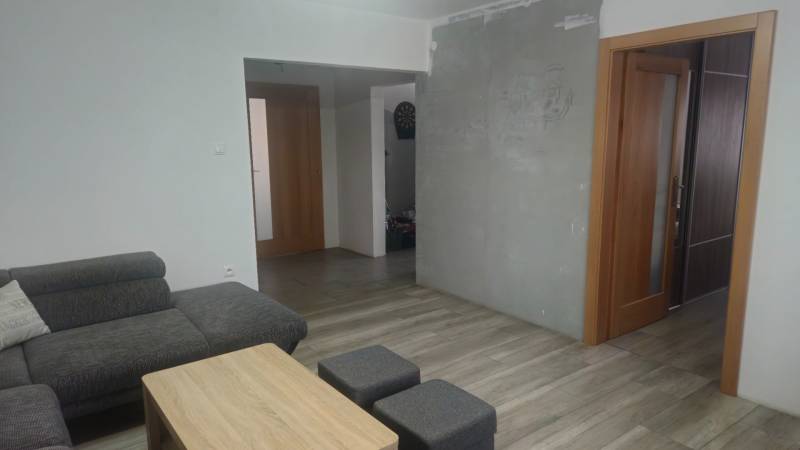 Living room in a family house, gray sofa, wooden coffee table, floor with wooden decor.