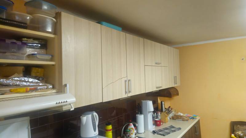 A kitchen in a family house with wooden cabinets and accessories on the kitchen counter.