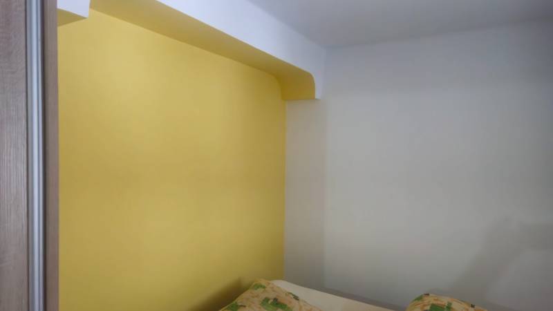 Yellow wall in a room of a family house with a pillow on the right.