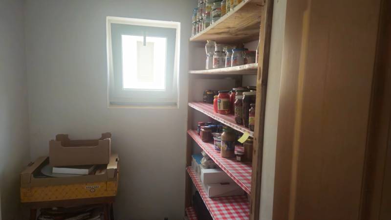 Food storage in the pantry of a family house with shelves full of preserves and cartons.