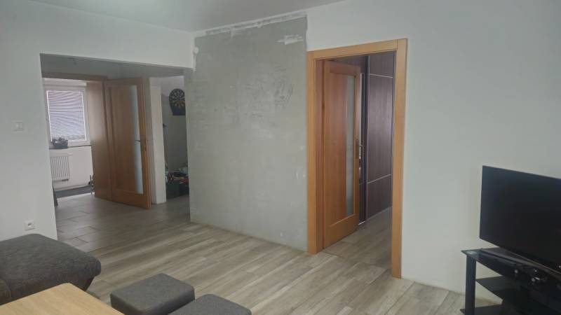 Interior of a family house with a wooden decor floor, a television, and open doors.