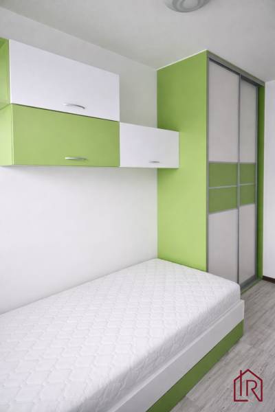 Single bed with storage cabinets in a 3-room apartment, floor with wooden decor.