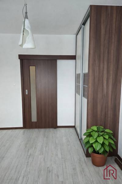 Interior of a 3-room apartment with a wooden decor floor, a large wardrobe, and sliding doors.