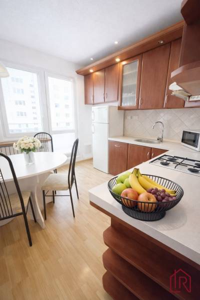 A kitchen in a 3-room apartment with a wooden decor floor and fruit on the table.