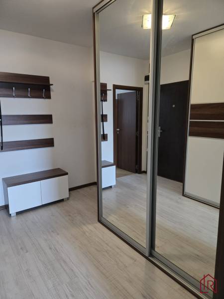 Entrance hall with a mirrored wardrobe and a floor with a wooden decor in a 3-room apartment.
