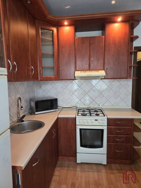 A kitchen in a 3-room apartment with a wood-decor floor and wooden cabinets.