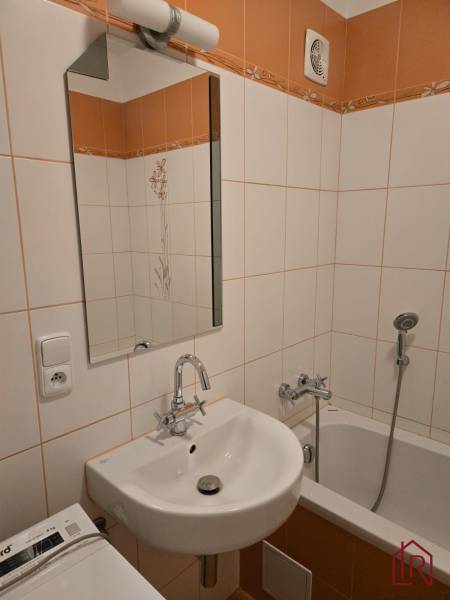 A bathroom in a 3-room apartment with a sink, bathtub, and orange tiles.