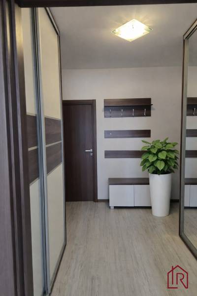 A hallway with a closet, hangers, a mirror, and a floor with a wooden decor in a 3-room apartment.