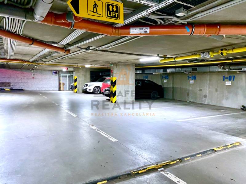 Underground garages with vehicles in parking spaces and elevator signs.