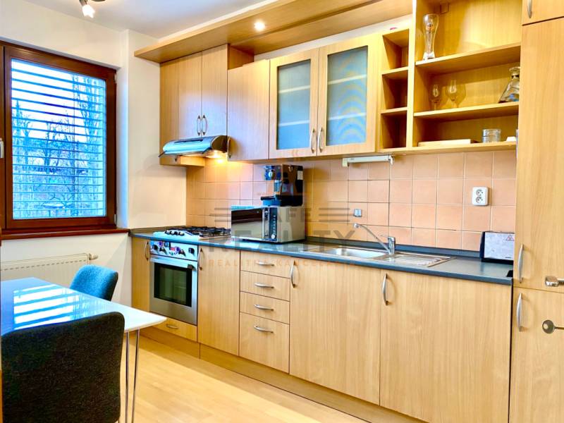 A kitchen with wooden decor, appliances, and a dining table in a two-room apartment.