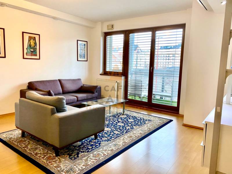 Living room with a sofa, an armchair, a carpet, and a large window in a 2-room apartment.
