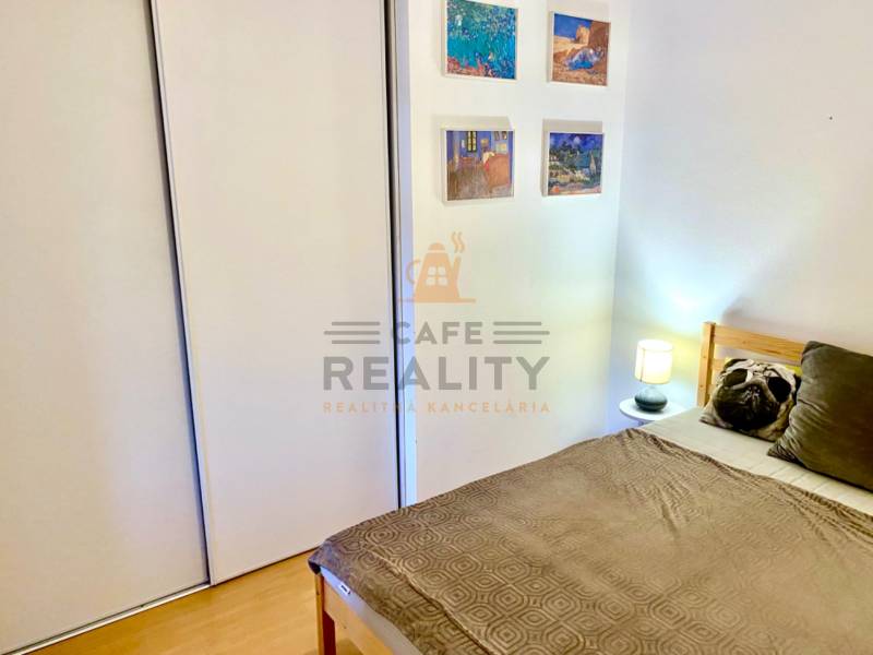 Bedroom in a 2-room apartment with a bed, built-in wardrobe, and wall decorations.