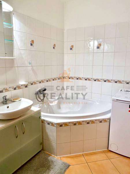 Bathroom with tiles, bathtub, and washing machine in a 2-room apartment.