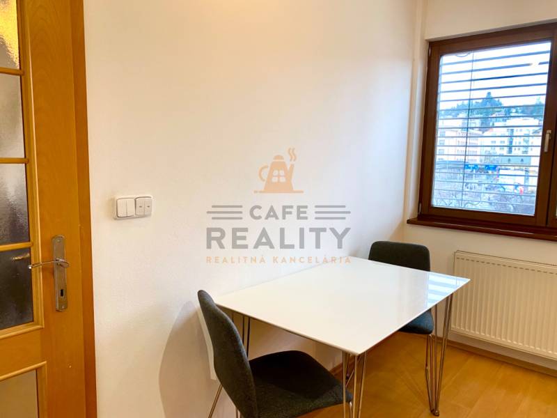 Dining area with a white table and chairs in a 2-room apartment, floor with wood decor.