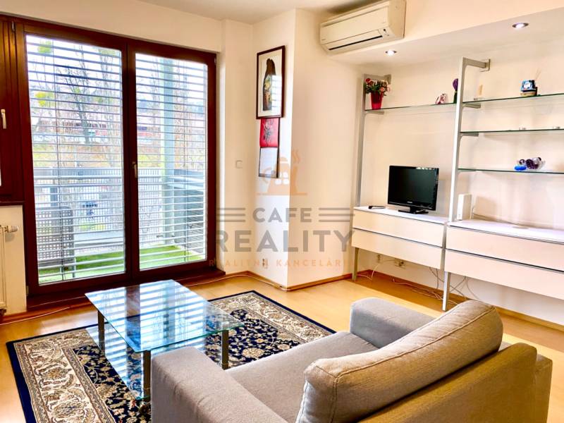 Living room in a 2-room apartment with an armchair, a glass table, and a floor with a wood decor.