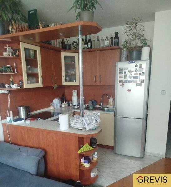 Compact kitchen in a studio apartment with a corner unit, refrigerator, and shelves.