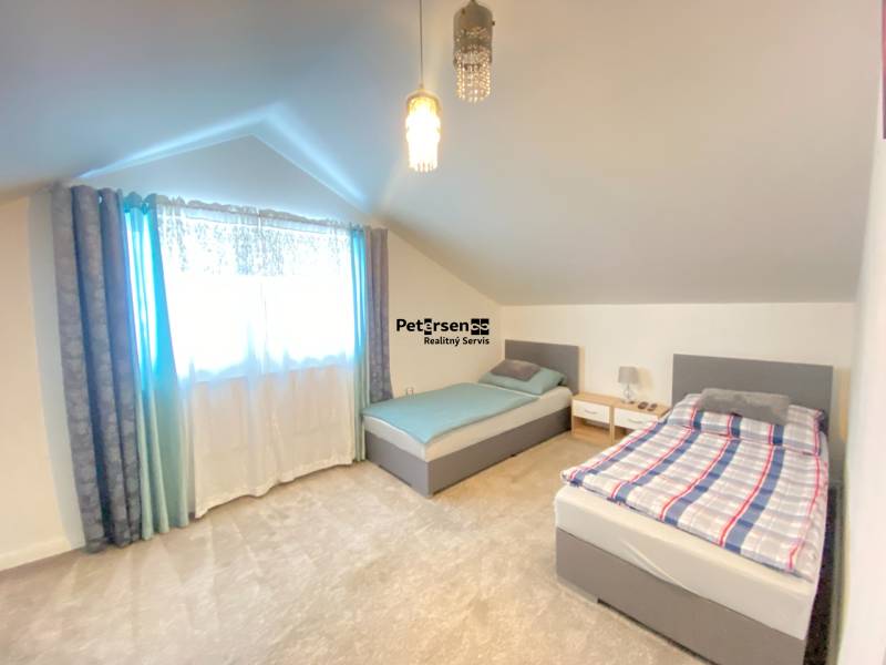 Attic room with two beds and a soft carpet in a family house.