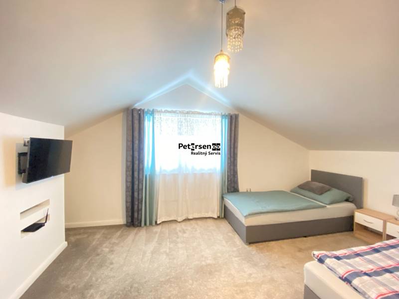 Bedroom in a family house with two beds, a television, and carpeted flooring.
