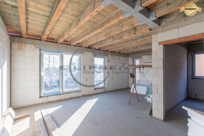The interior of an unfinished building with a wooden ceiling and large windows.