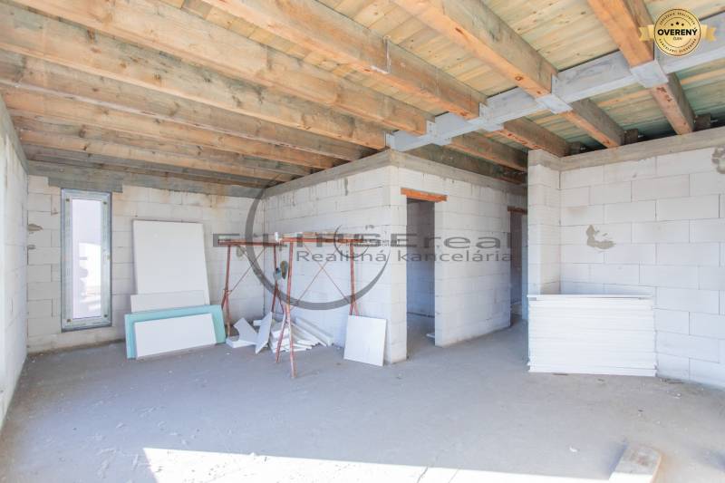 A building under construction with a wooden ceiling and construction materials inside.