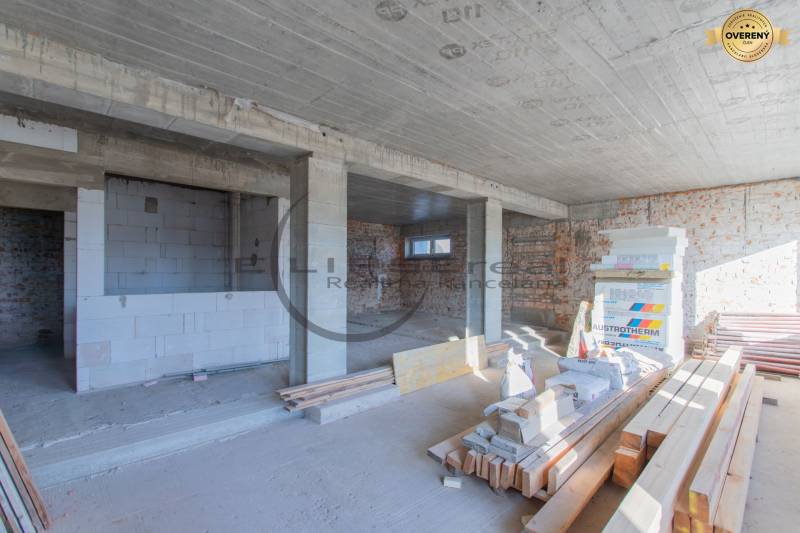 The interior of a building under construction with an uneven brick wall and construction materials on the floor.