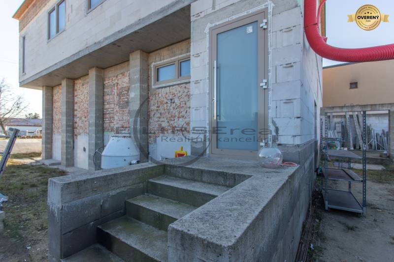 A building in Veľké Leváre with an unfinished facade and stairs on a concrete base.