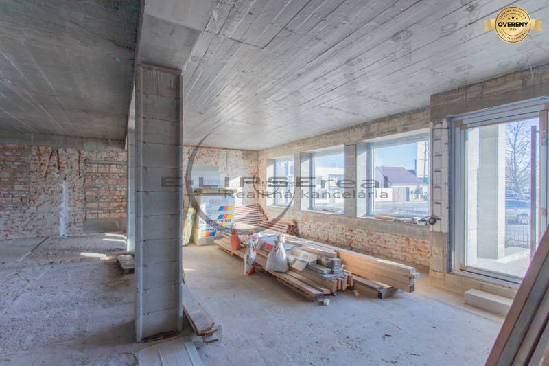 Interior of a building with brick walls, large windows, and construction materials.