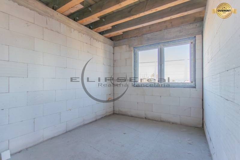 An empty room with white walls, a wooden ceiling, and a large window in a building.