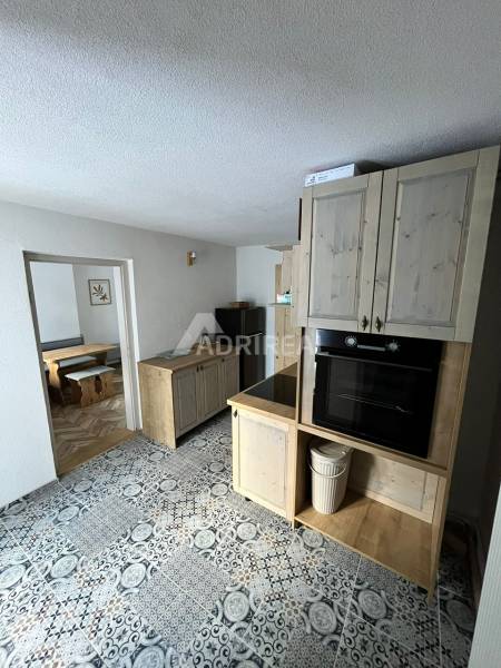 A kitchen in a family house with patterned tiles and kitchen cabinets with a wood decor.