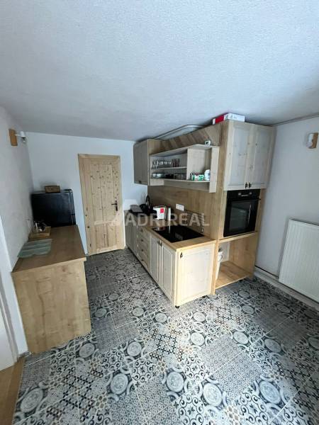 A kitchen in a family house with tiles and wooden cabinets, equipped with an oven and wood.