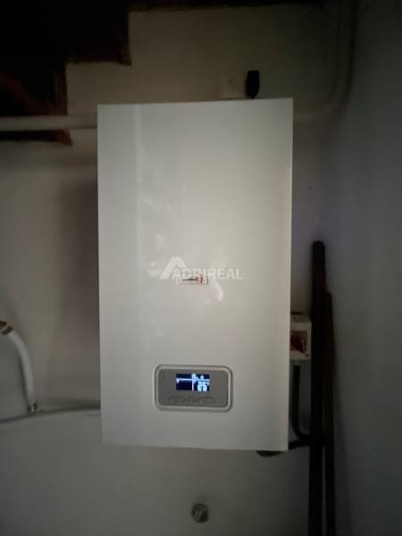A condensing boiler in the interior of a family house with the current temperature displayed on the screen.