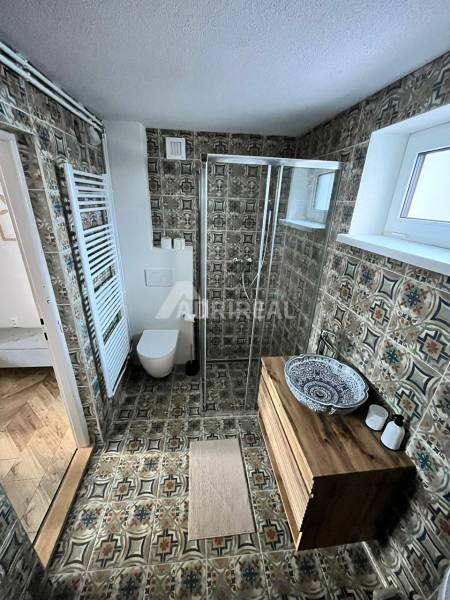 A bathroom in a family house with decorative tiles and a wooden washbasin table.