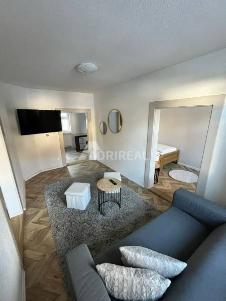 A family house with a sofa, television, mirrors, and a floor with a wooden decor.