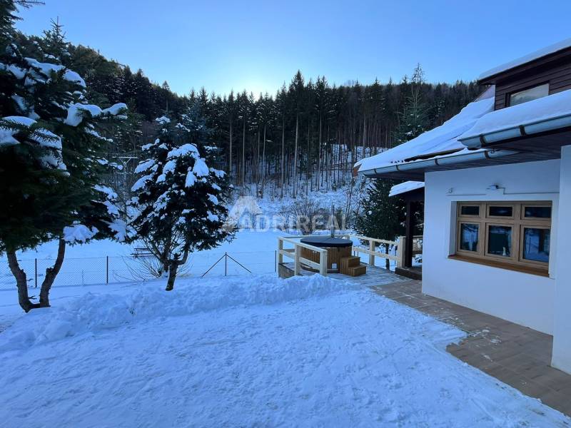 A family house in Bystrá on a snowy street with a view of the forest and snowy landscape.