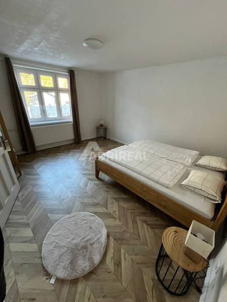 A bedroom in a family house with a wooden decor floor and a wooden bed.
