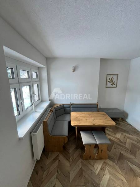 Dining area with a sofa and a wooden table on a floor with a wooden decor in a family house.
