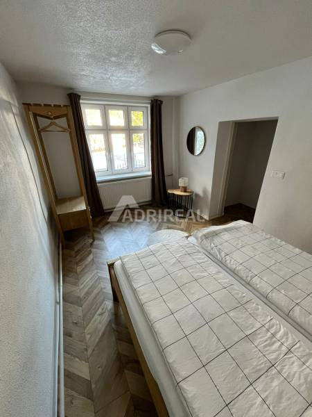 Bedroom in a family house with a wooden decor floor and a large window.