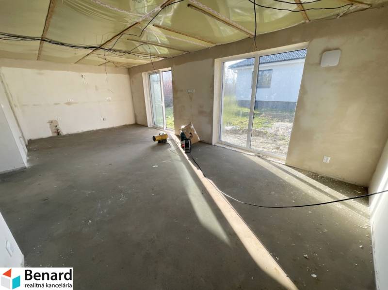 An empty room with large windows in a family house, without floor covering.