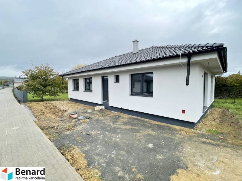 A family house in Sol with a white facade and a sloped roof, surrounded by a garden.