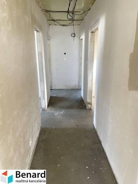 A hallway of a family house with an unfinished ceiling and a concrete floor.