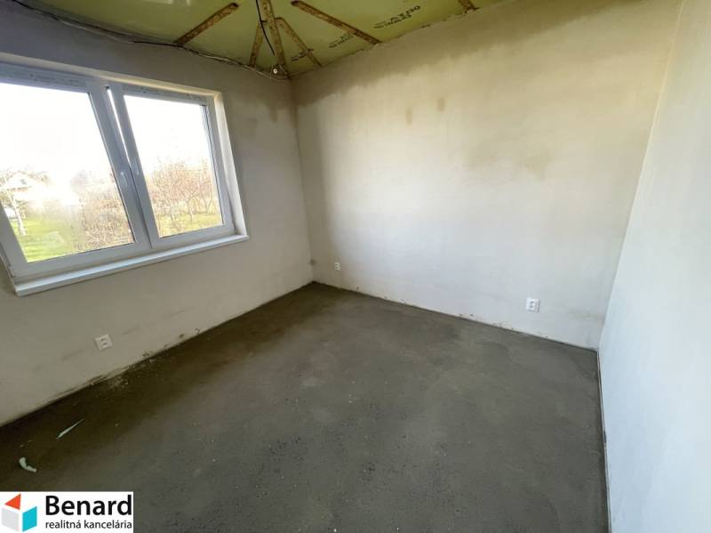 An empty room in a family house with plastered walls and a concrete floor.