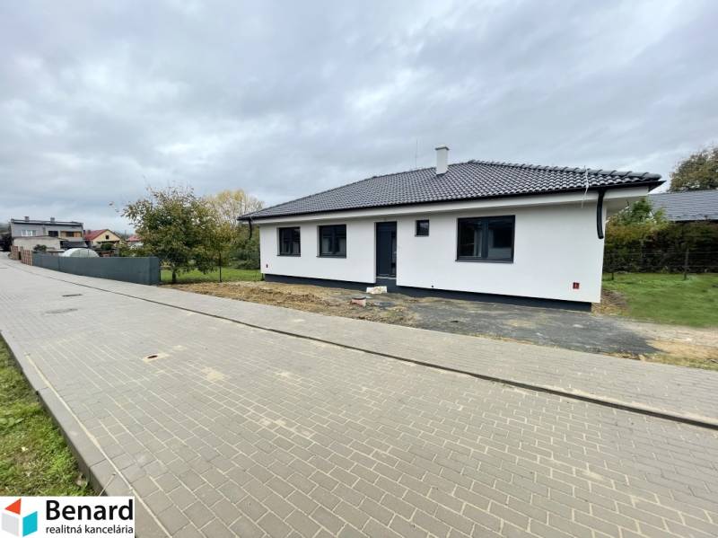 A family house in the village of Soľ with a white-gray facade, surrounded by a paved walkway.