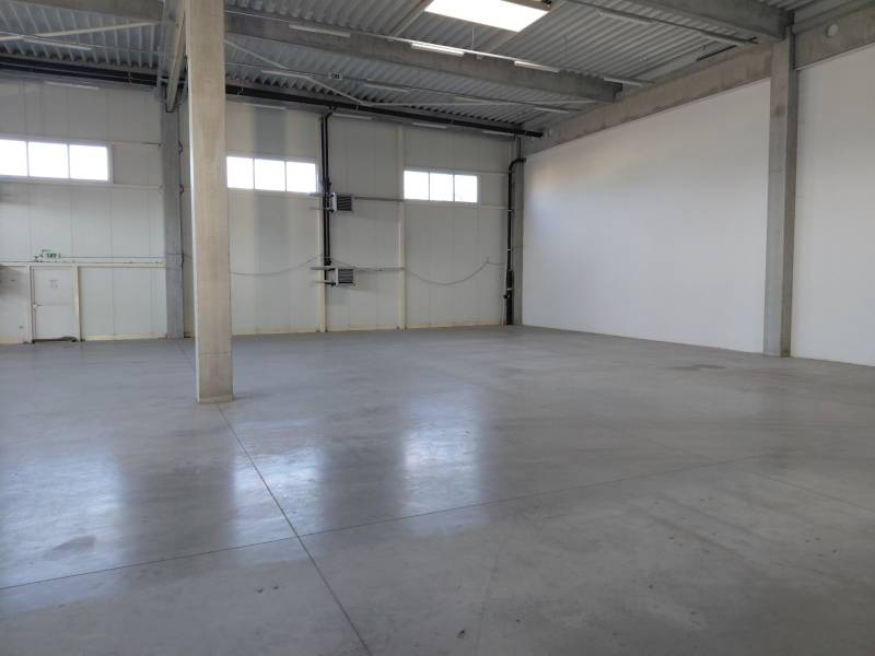 Spacious interior of warehouses and halls with concrete flooring and high ceilings.