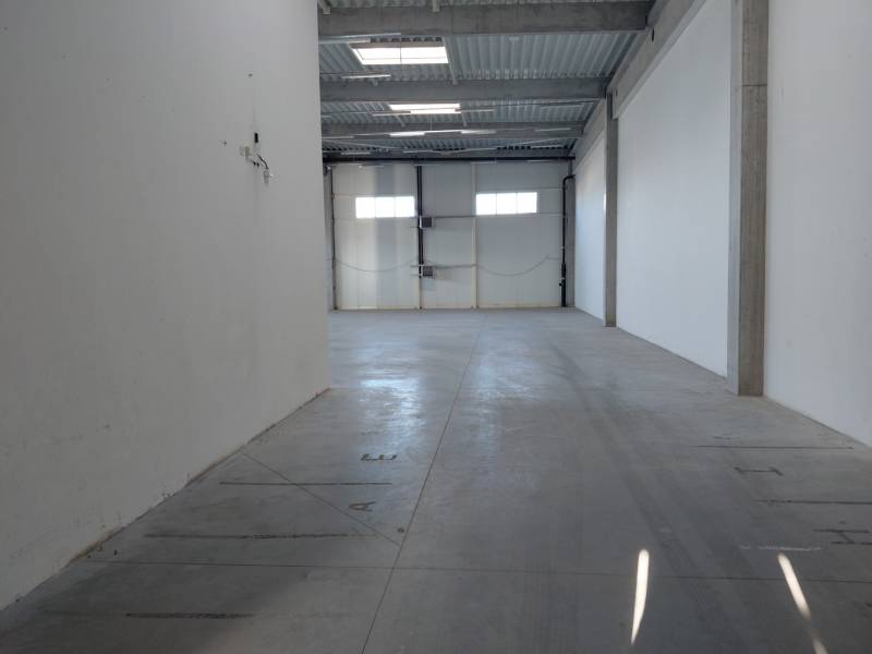 Empty interior of warehouses and halls with white walls and concrete floor.
