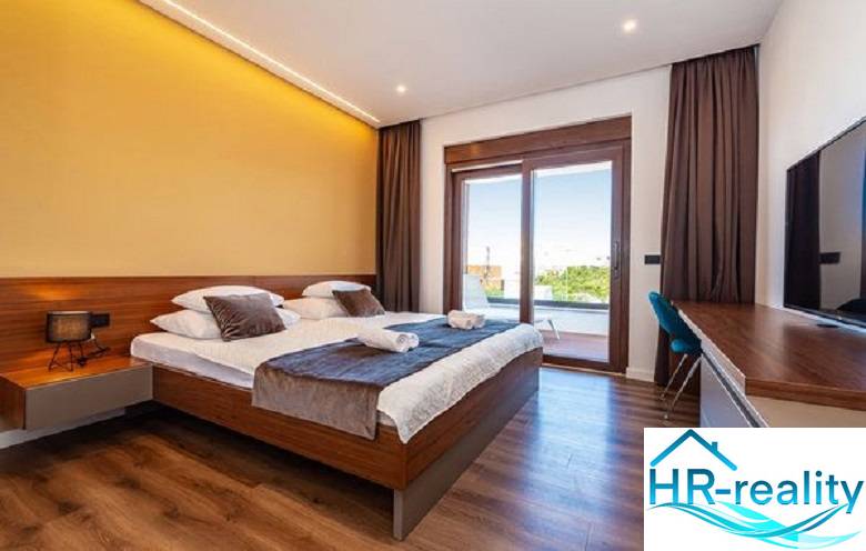 Elegant bedroom in a villa with a bed and wooden decor flooring.