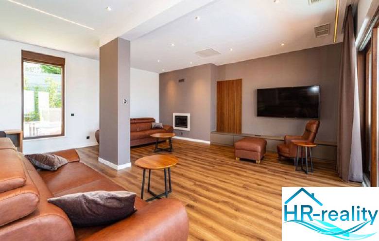 Living room in a villa with wood-patterned flooring, a leather sofa, and a television.