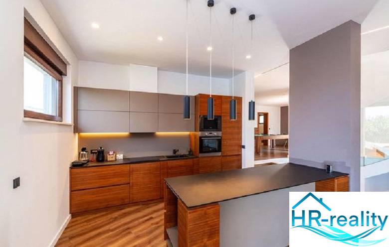 A kitchen in a villa with a wood-patterned floor and stylish lighting.