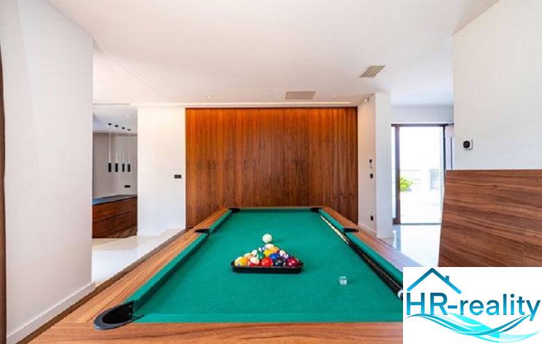 A billiard table in the interior of a villa with a wooden decor floor.